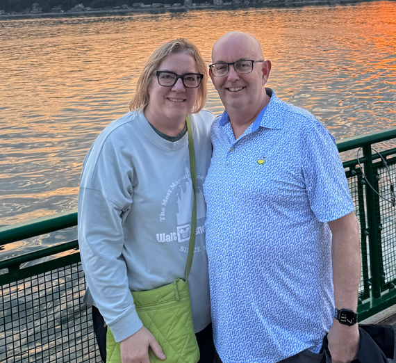A group of guys smiles and waves at the camera. 