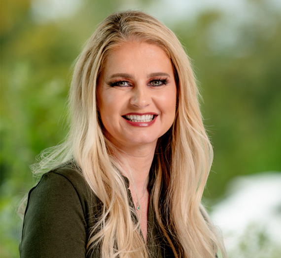 Группа из пяти человек стоит вместе в ярко освещенном коридоре больницы, улыбаясь в камеру. Двое носят стетоскопы и медицинскую одежду, один — толстовку Университета Гонзага, остальные одеты в повседневную или деловую одежду, представляя смесь студентов и медицинских работников.